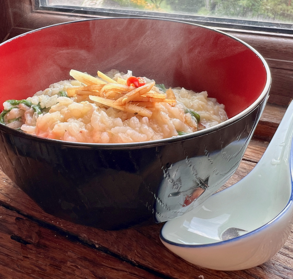 Bowl of creamy Asian rice porridge (Juk) garnished with fresh ginger, chili slices, and a splash of vinegar